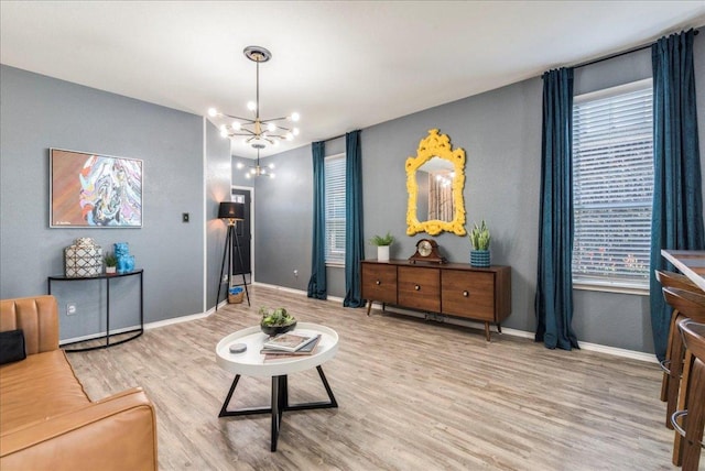 living area with wood finished floors, baseboards, and a chandelier