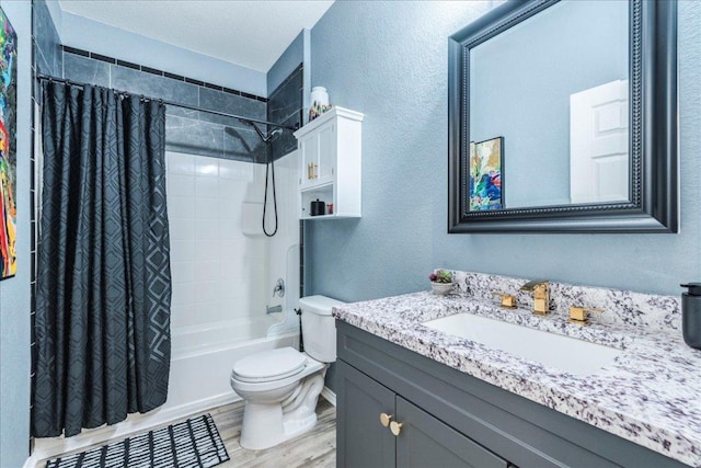 full bathroom with toilet, wood finished floors, shower / tub combo, vanity, and a textured wall