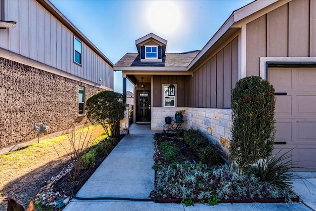 property entrance with a garage, board and batten siding, and stone siding