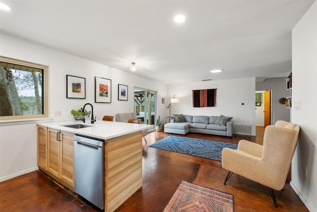 kitchen featuring light brown cabinetry, a sink, a peninsula, baseboards, and dishwasher