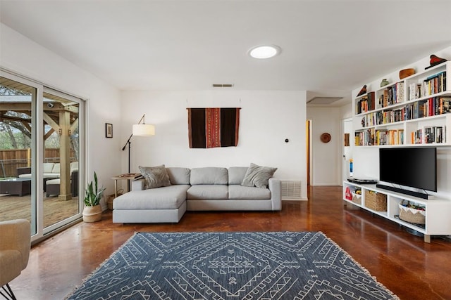 living area featuring visible vents, attic access, and finished concrete floors