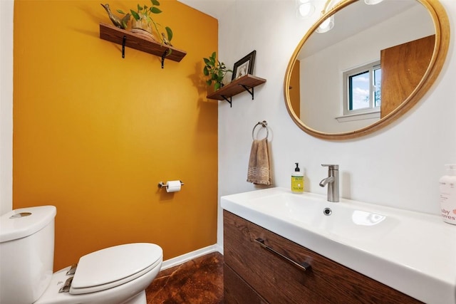 bathroom featuring toilet, vanity, and baseboards