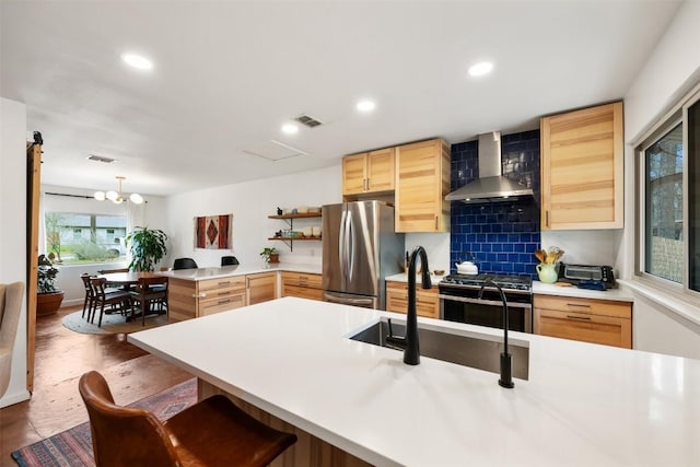 kitchen with visible vents, light brown cabinets, wall chimney range hood, a peninsula, and stainless steel appliances