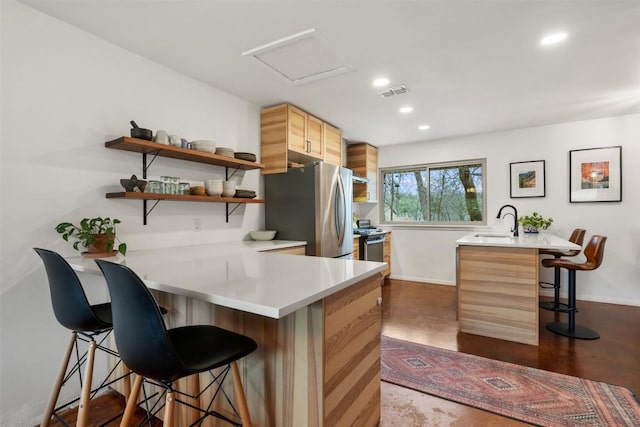 kitchen featuring a kitchen bar, visible vents, a sink, open shelves, and stainless steel appliances