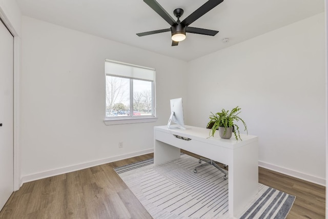 unfurnished office with ceiling fan, baseboards, and wood finished floors