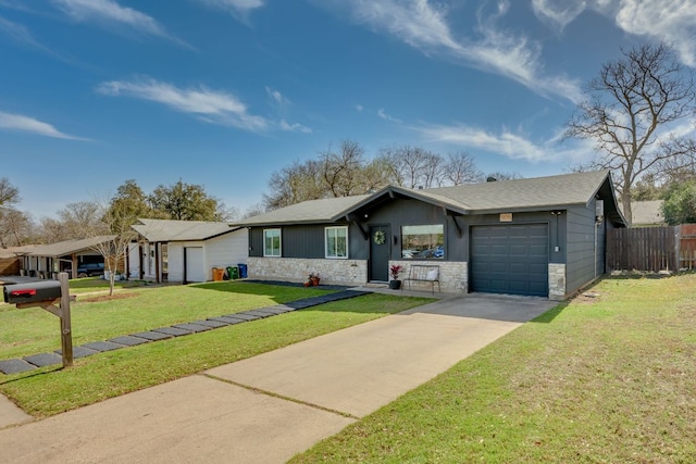 view of front facade featuring a front yard, fence, driveway, a garage, and stone siding