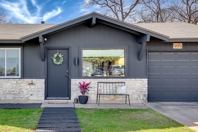 entrance to property with stone siding, a shingled roof, and a garage