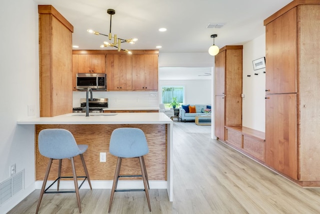 kitchen featuring light wood-type flooring, visible vents, a kitchen breakfast bar, and appliances with stainless steel finishes