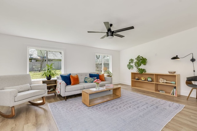 living area featuring baseboards, ceiling fan, and wood finished floors