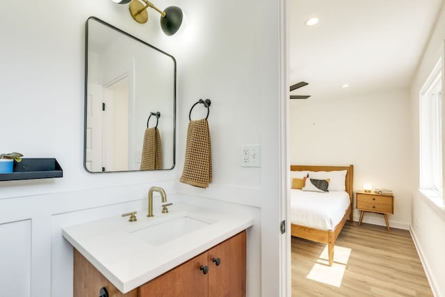 bathroom with recessed lighting, baseboards, wood finished floors, and vanity