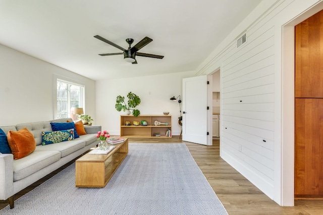 living room featuring light wood-style flooring, a ceiling fan, and visible vents