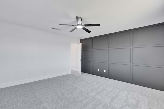 unfurnished bedroom featuring visible vents, baseboards, carpet flooring, a decorative wall, and a ceiling fan