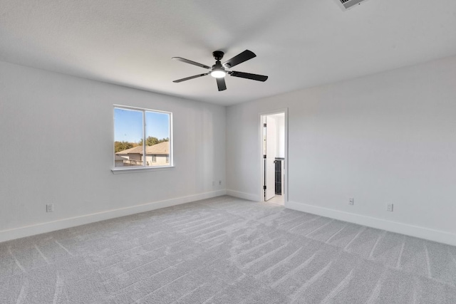 spare room featuring visible vents, light colored carpet, a ceiling fan, and baseboards