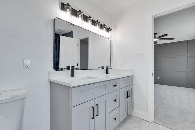 bathroom with a sink, toilet, ceiling fan, and double vanity