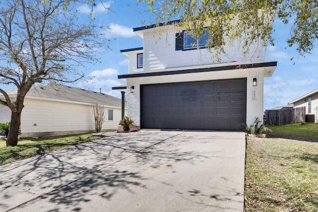 garage with concrete driveway and fence