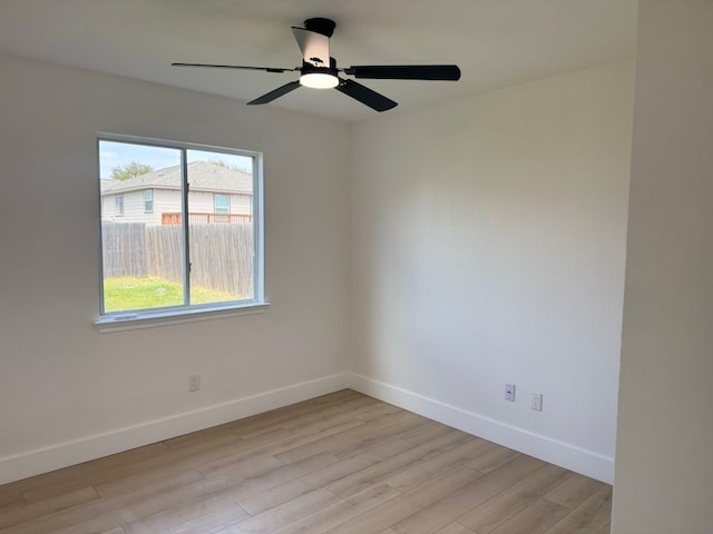 spare room featuring baseboards, light wood-style floors, and ceiling fan