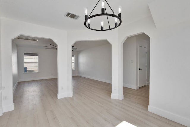 spare room with arched walkways, visible vents, ceiling fan with notable chandelier, and light wood-style flooring