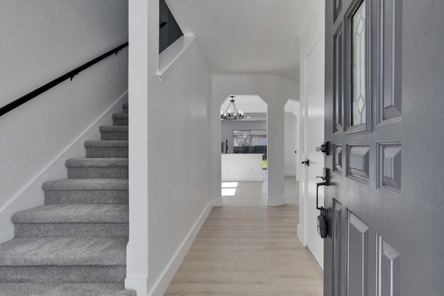 entryway with a chandelier, stairway, light wood-style flooring, and baseboards