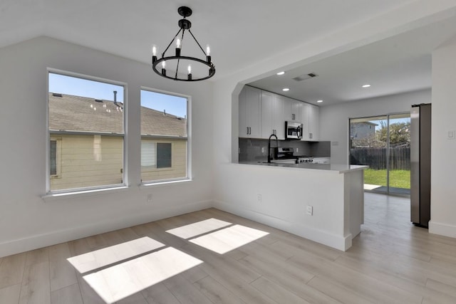 unfurnished dining area featuring visible vents, recessed lighting, arched walkways, a notable chandelier, and light wood-type flooring