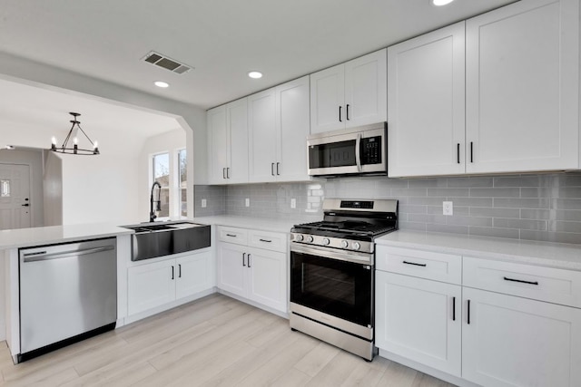 kitchen with visible vents, a sink, backsplash, stainless steel appliances, and light countertops