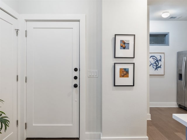 foyer entrance featuring wood finished floors, visible vents, and baseboards