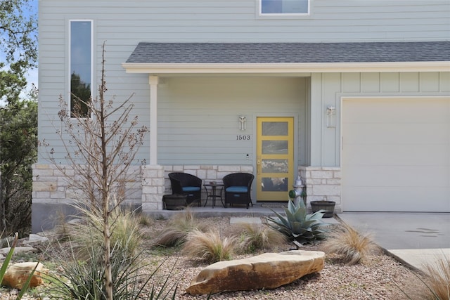 view of exterior entry with a porch, stone siding, board and batten siding, and roof with shingles