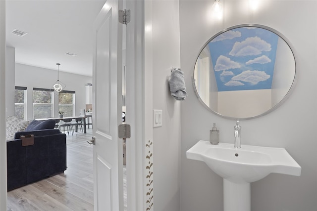 bathroom featuring wood finished floors, visible vents, and a sink