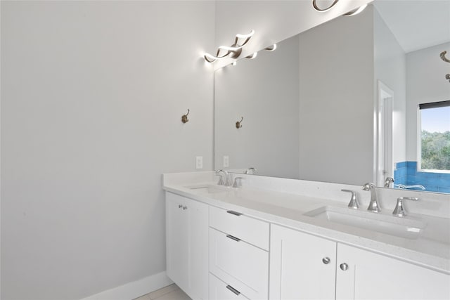 full bath with tile patterned flooring, double vanity, baseboards, and a sink