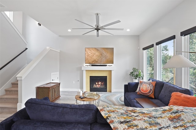 living area with wood finished floors, stairway, recessed lighting, and a warm lit fireplace