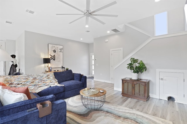 living room with stairs, wood finished floors, visible vents, and baseboards