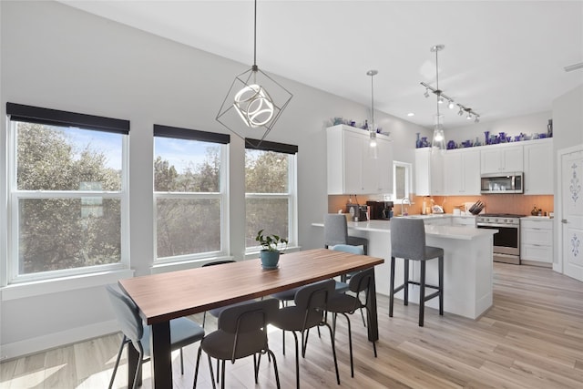 dining area with light wood-type flooring, baseboards, and visible vents