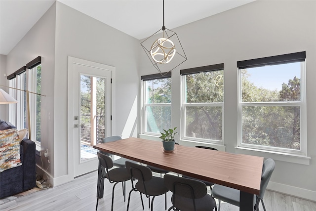 dining space with light wood finished floors, a chandelier, and baseboards