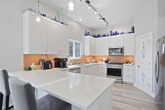1503 Sharps Rd, Austin, TX 78734 - kitchen featuring stainless steel appliances, a peninsula, white cabinets, light wood-type flooring, and decorative backsplash