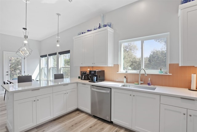 kitchen with a sink, a peninsula, white cabinets, light countertops, and dishwasher