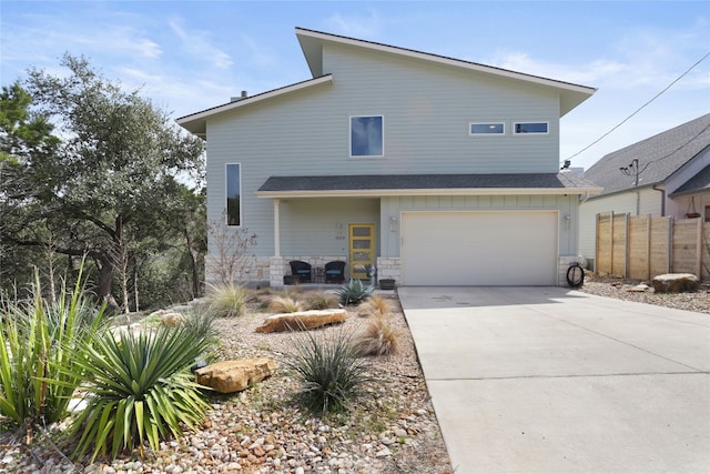 view of front facade with board and batten siding, driveway, a garage, and fence