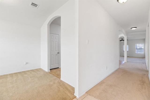 corridor featuring light carpet, visible vents, and arched walkways