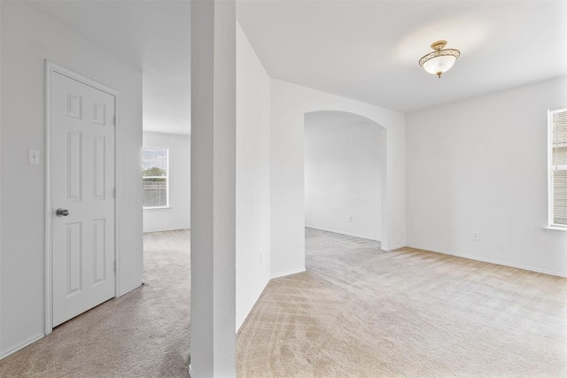 carpeted spare room featuring arched walkways