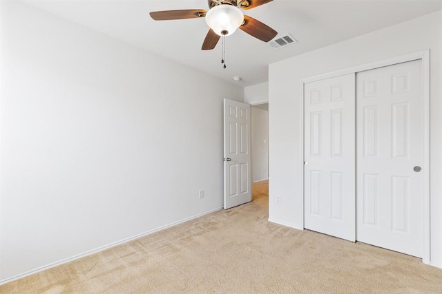 unfurnished bedroom with visible vents, light colored carpet, a closet, and ceiling fan