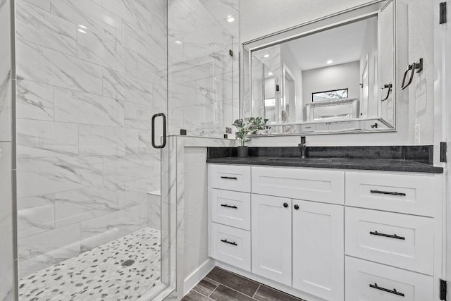 bathroom with a marble finish shower, vanity, and wood finish floors