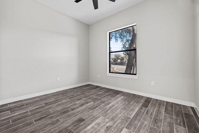 empty room featuring dark wood finished floors, a ceiling fan, and baseboards