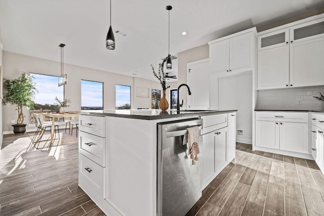 kitchen with wood finish floors, a sink, backsplash, dark countertops, and dishwasher