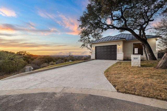 exterior space with concrete driveway, stucco siding, metal roof, stone siding, and a standing seam roof