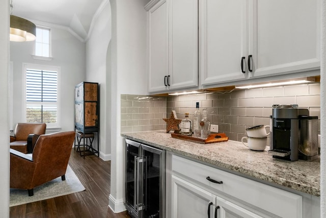 kitchen featuring beverage cooler, light stone counters, decorative backsplash, white cabinets, and dark wood-style flooring