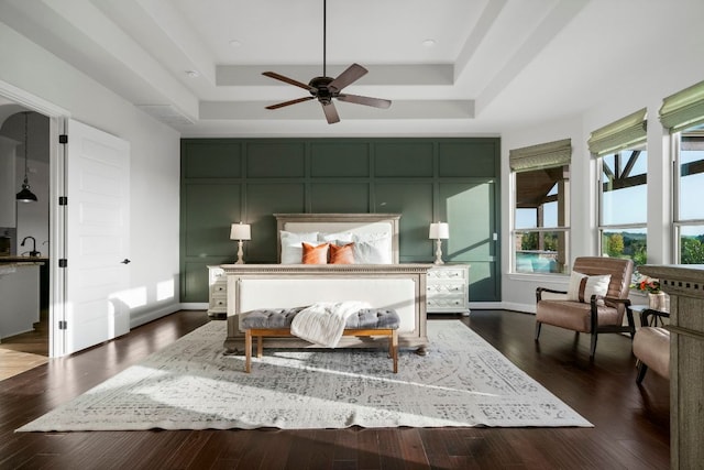 bedroom with baseboards, a raised ceiling, and dark wood-style floors