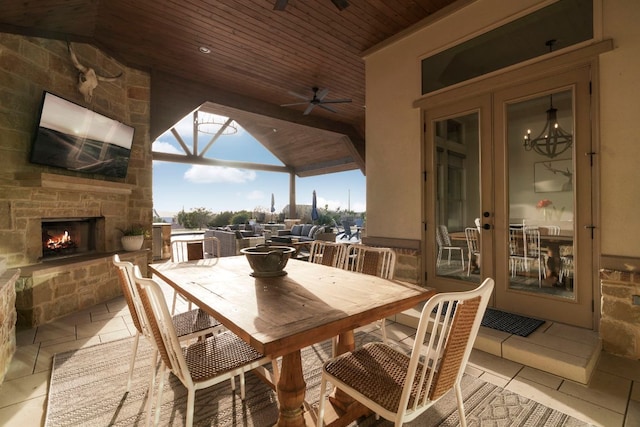 view of patio with outdoor dining area, an outdoor stone fireplace, and a ceiling fan