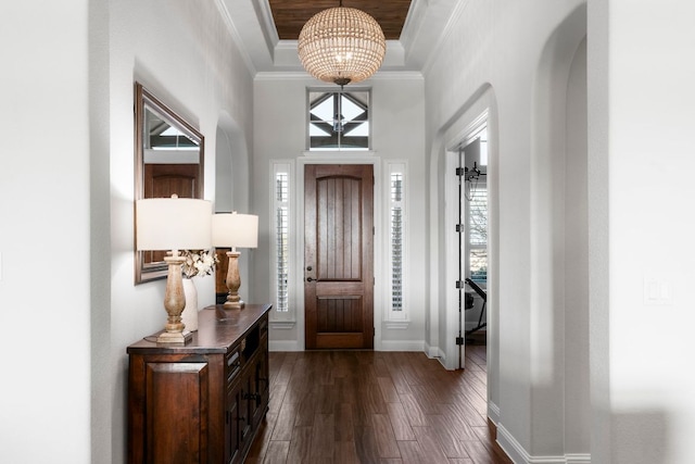 foyer entrance with crown molding, baseboards, a chandelier, a tray ceiling, and dark wood-style floors