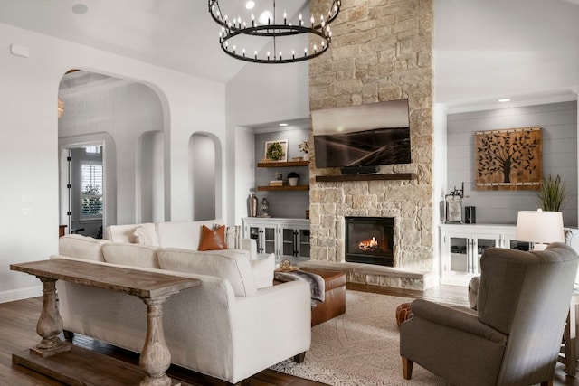 living area featuring wood finished floors, arched walkways, a high ceiling, a fireplace, and baseboards