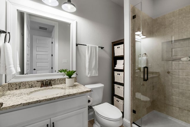 full bathroom with vanity, a shower stall, toilet, and visible vents