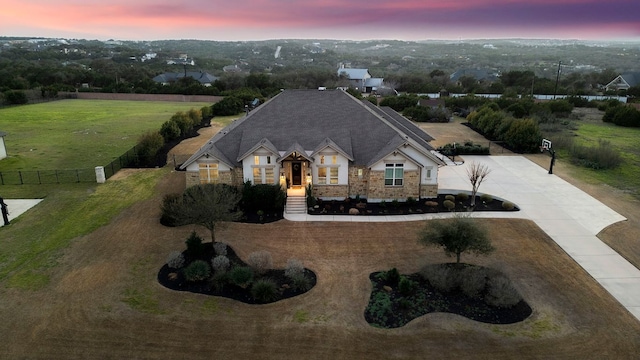 view of front of property featuring concrete driveway, fence, and stone siding