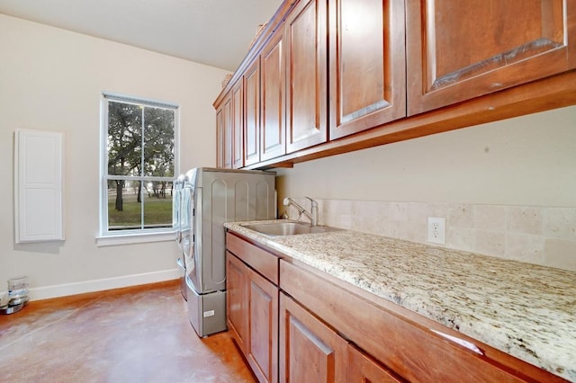 washroom featuring a sink, baseboards, cabinet space, and independent washer and dryer